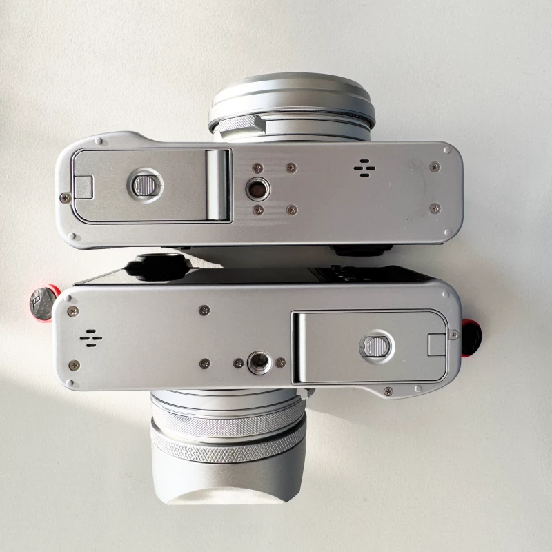 Fujifilm X100V and X100VI bottom back to back showing the different location of the tripod thread