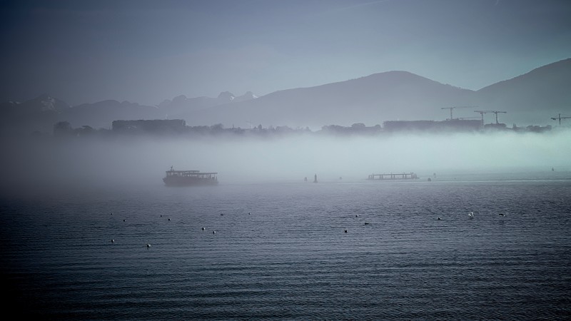 A layer of fog above the lake with a boat shrouded in it